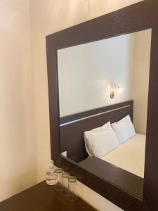 a mirror above a bed with glasses on a table at Hotel Alkionis in Ierissos