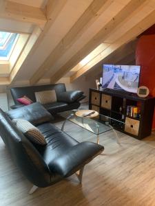 sala de estar con sofá de cuero negro y TV en Tolles Loft in den Tessiner Bergen, en Corcapolo