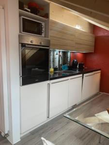 a kitchen with white cabinets and a microwave at Tolles Loft in den Tessiner Bergen in Corcapolo