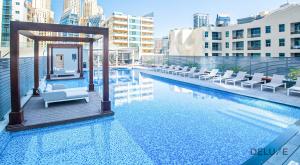 a hotel swimming pool with chairs and a gazebo at Airy Studio in Studio One Dubai Marina by Deluxe Holiday Homes in Dubai