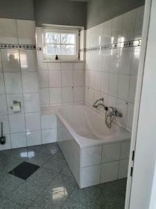 a white bathroom with a tub and a window at Ferienwohnung Annaburg in Merzig