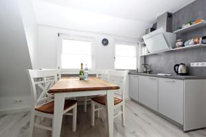 a kitchen with a wooden table and white cabinets at Senhues-App-7 in Hörnum