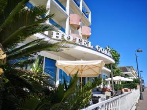 un hotel en la playa con una sombrilla y una palmera en Hotel Gorini, en Bellaria-Igea Marina