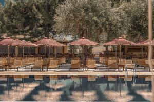 a group of chairs and umbrellas next to a pool at Cook's Club Corfu - Adults Only in Gouvia