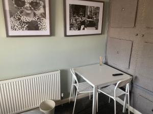 een tafel en stoelen in een kamer met foto's aan de muur bij Wellbrook Rooms in Tring