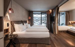 a bedroom with two beds and a table and a window at Falkensteiner Family Resort Lido Superior in Chienes