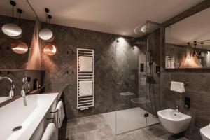 a bathroom with a sink and a toilet and a shower at Falkensteiner Family Resort Lido Superior in Chienes