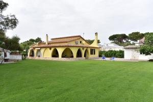 una grande casa gialla con un grande cortile verde di villa Letizia a Pula