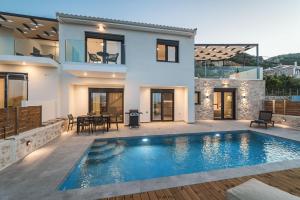 a villa with a swimming pool in front of a house at Nemesis Luxury Villas in Apolpaina