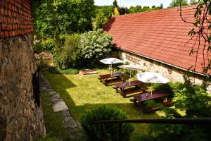 a row of wooden benches with umbrellas in a yard at Hostinec a penzion U Rezků in Jistebnice