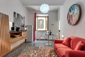 sala de estar con sofá rojo y cocina en Vedetta Townhouse - camere e appartamenti nel centro storico by Be Vedetta, en Scarlino