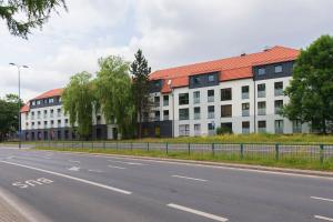 a building with a red roof on the side of a road at Apartment City Centre Netflix- GreenPark - River in Olsztyn