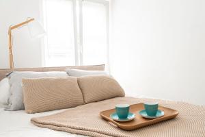 a tray with two blue cups on top of a bed at Apartment City Centre Netflix- GreenPark - River in Olsztyn