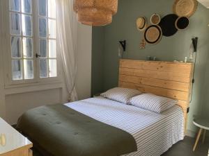 Maison de pêcheur 1900 في سانت-ماندرييه-سور-مير: غرفة نوم مع سرير مع اللوح الأمامي الخشبي والنوافذ