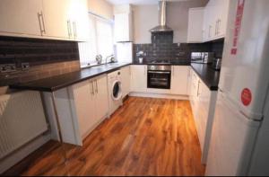 a kitchen with white cabinets and a wooden floor at Host Liverpool - City Centre Townhouse, Group Friendly & Parking in Liverpool
