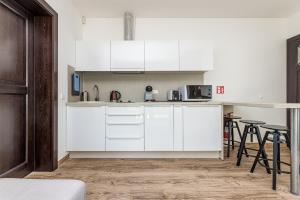 a white kitchen with white cabinets and a table at VILLA AIDO in Palanga