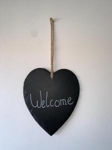 Ein schwarzes Herz hängt an einer Wand mit dem Wort Willkommen in der Unterkunft Appartement Vila Fajen in Sukošan