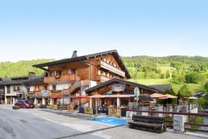 ein großes Holzgebäude an der Straßenseite in der Unterkunft Loc'Hotel Alpen Sports in Les Gets