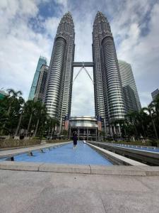 a person walking on a bridge in front of tall buildings at CUSHY DORM at KLCC in Kuala Lumpur