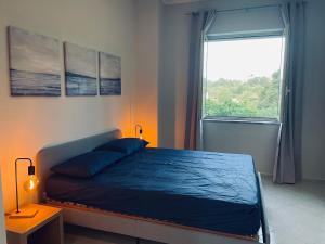 1 dormitorio con 1 cama con edredón azul y ventana en Villa Sibilla, en Bacoli
