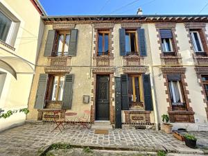 stary budynek z czarnymi drzwiami i oknami w obiekcie Maison de ville - Paris en 15 mn ! - 4 pers- 1 bébé - Vintage & Music ! w mieście Groslay