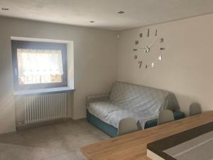 a living room with a couch and a clock on the wall at Senin House in Aosta