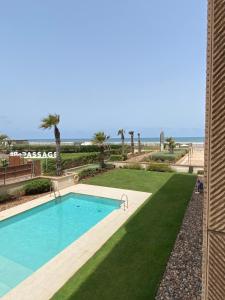 a swimming pool with a lawn and the beach at Anfa Place, Art Deco Luxury Apartment, Sunny Ocean View in Casablanca
