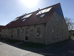 un grand bâtiment en briques avec des fenêtres et un toit dans l'établissement Koestal, à Hollum