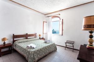 um quarto com uma cama e uma janela em Hotel Carasco em Lipari