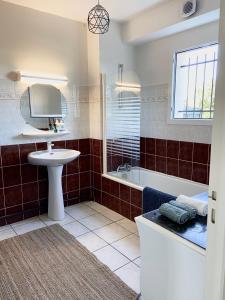 La salle de bains est pourvue d'un lavabo, d'une baignoire et d'un miroir. dans l'établissement Grand appartement en résidence calme avec piscine, à Saint-Paul-lès-Dax