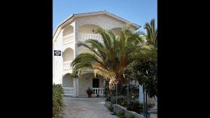 a building with a palm tree in front of it at Apartment 5, first floor in Rogoznica