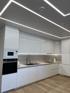 a white kitchen with a sink and a microwave at Apartamentai Pas Liną in Nida