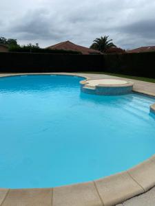 a large swimming pool with blue water at Grand appartement en résidence calme avec piscine in Saint-Paul-lès-Dax