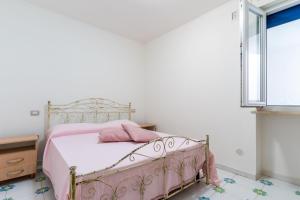 Cama rosa en habitación con ventana en Residence La Perla - Opale, en Pizzo