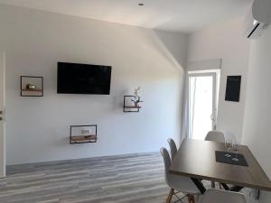 a dining room with a table and a tv on a wall at Appartement Vila Fajen in Sukošan