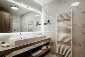 ein weißes Badezimmer mit einem Waschbecken und einem Spiegel in der Unterkunft Hotel Vivat in Moravske-Toplice