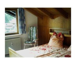 a bedroom with a bed and a chair and a window at Haus-Bucheneck-Wohnung-Sonnenaufgang in Oberstdorf