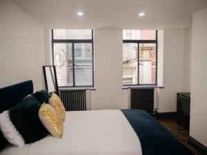 a bedroom with a bed with pillows and two windows at New Oxford House Apartments By Happy Days in Liverpool