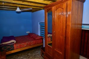 a bedroom with a bed and a wooden cabinet at Kollakudy HomeStay in Paravūr