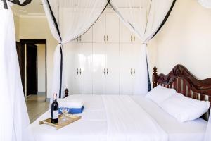 - une chambre avec un lit blanc et un plateau de verres à vin dans l'établissement Luxury Acacia Villa with Kampala's Best View, à Kampala