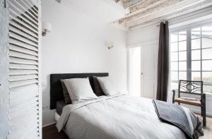 - une chambre blanche avec un lit et une fenêtre dans l'établissement Appartement Gérard, tout équipé Paris 13éme, à Paris