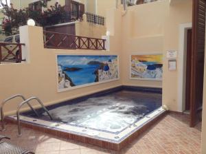 a large swimming pool in a building with paintings on the wall at Antonia Apartments in Fira