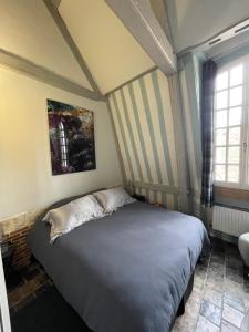 een slaapkamer met een bed in een kamer met gestreepte muren bij Le Loft du Homard Bleu - entre Ciel et Mer - Free Parking 500m in Honfleur