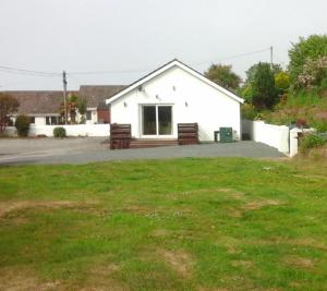 a white building with a bench in front of a yard at Lovely 3 Bedroom Bungalow Located in Drummore in Drummore