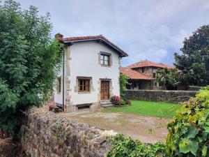 a white house with a stone wall and a yard at La Casuca de Agüero in Agüero