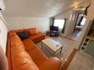 ein Wohnzimmer mit einem orangenen Sofa und einem Tisch in der Unterkunft Apartments Istra Nielsen in Premantura