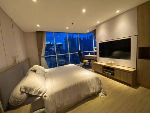 ein Schlafzimmer mit einem großen Bett und einem großen Fenster in der Unterkunft 3BR apt Springhill Terrace, golf view in Jakarta