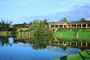 a large building with a lake and trees at Kloofzicht Lodge & Spa in Muldersdrift