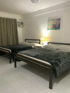 two twin beds in a bedroom with a lamp at Chillax Inn in Tagaytay