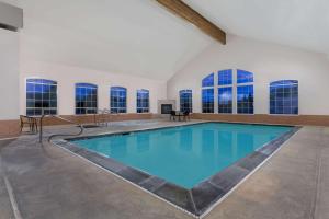 an indoor swimming pool with blue water in a room with windows at Super 8 by Wyndham Rexburg in Rexburg